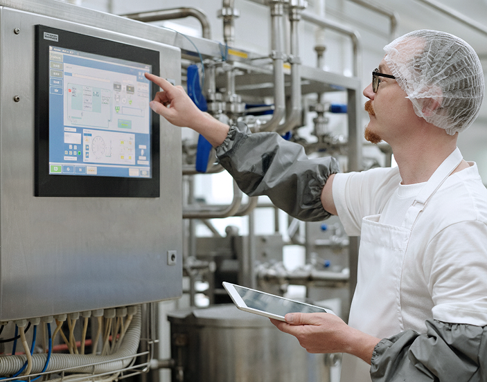 Factory operator using an Elo industrial touchscreen to manage production line automation and machine performance.